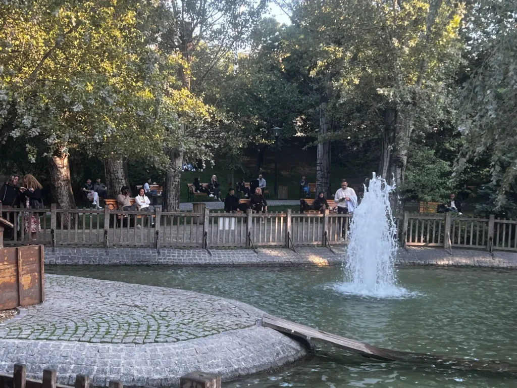 People sitting beside the pond and fountain in Kuğulu Park, Ankara