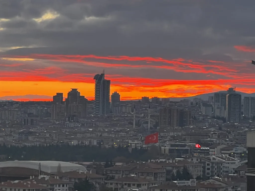 Ankara skyline silhouetted beneath a vivid orange and red sunset