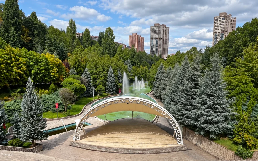 Covered amphitheater and fountains surrounded by trees, with apartment towers rising above Dikmen Vadisi in Ankara.