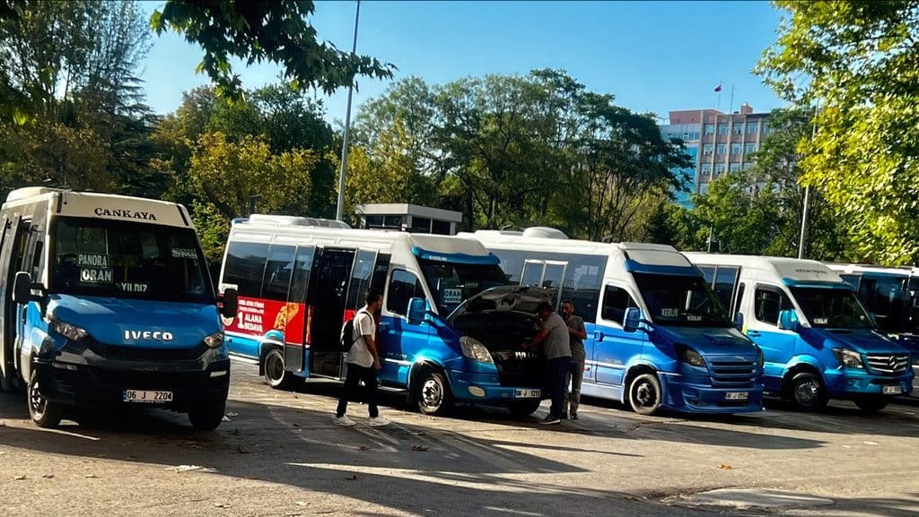 Blue-and-white dolmuş minibuses lined up at a departure area near Kızılay in Ankara, Türkiye.