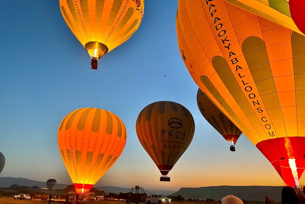 Close-up view of glowing hot-air balloons during sunrise in Cappadocia, Türkiye.