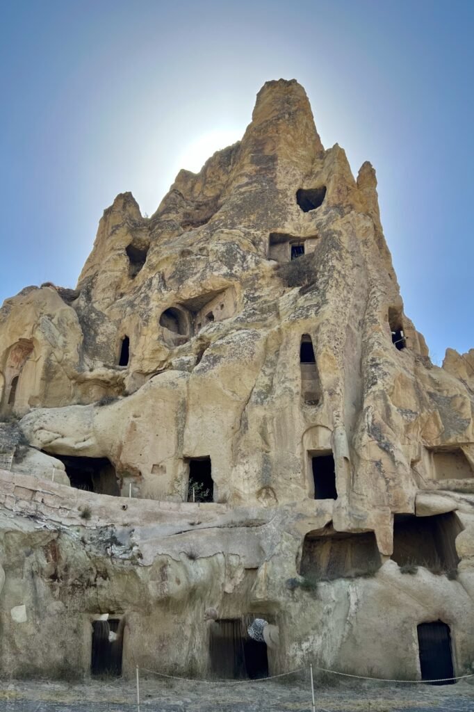 Rock-cut rooms and openings carved into a tall volcanic formation at Göreme Open-Air Museum in Cappadocia, Türkiye
