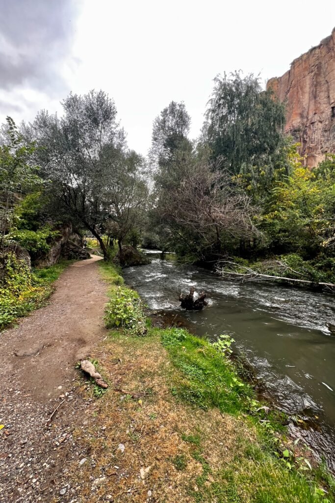 Walking trail beside the Melendiz River beneath steep canyon walls in Ihlara Valley, Türkiye