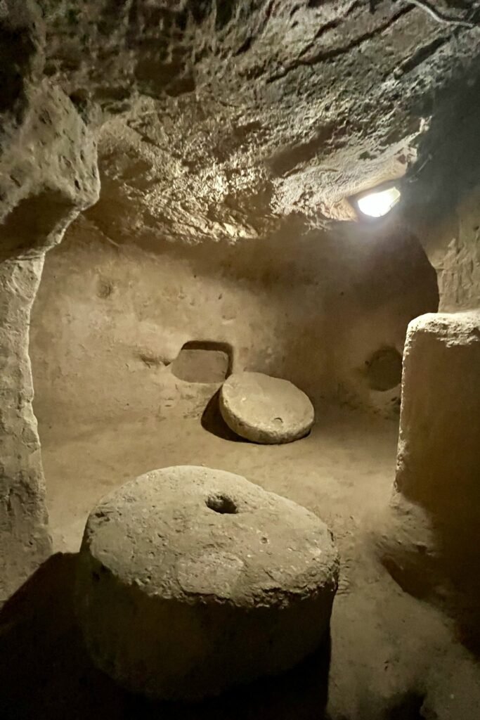 Circular stone millstones inside a carved chamber at Saratlı Underground City near Aksaray, Türkiye