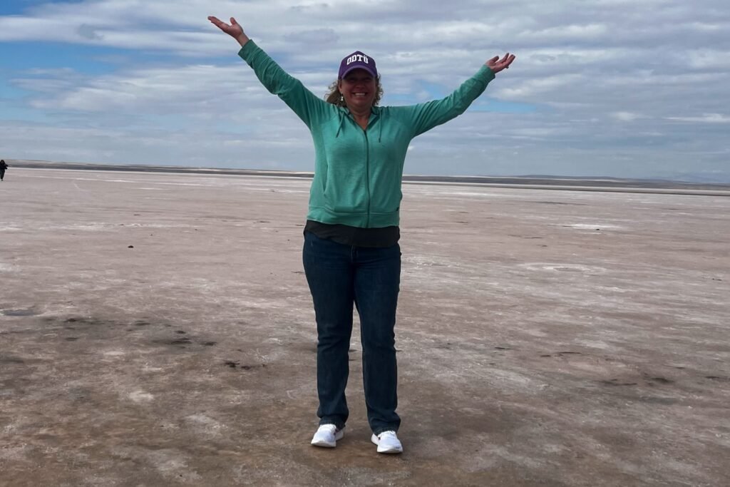 Woman standing on the dry salt flats of Tuz Gölü beneath a cloudy blue sky in central Türkiye