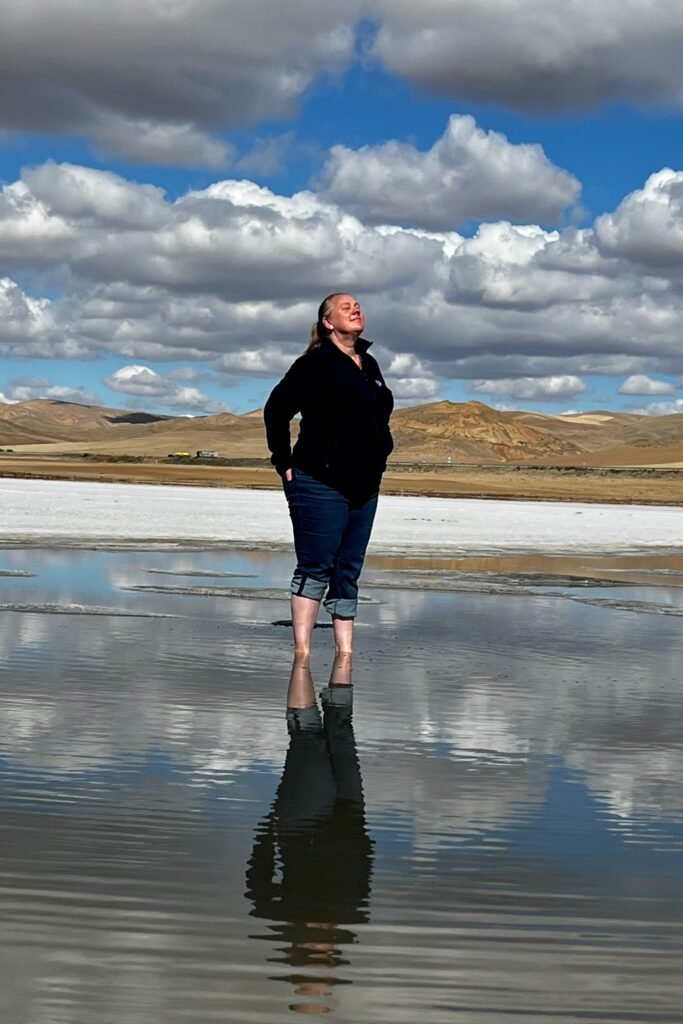 Tiffles standing in shallow water at Tuz Gölü with her reflection visible beneath a dramatic cloudy sky