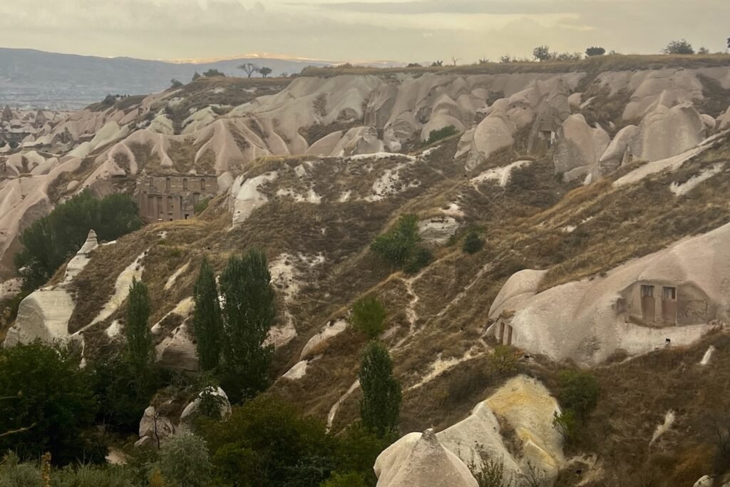 Pigeon Valley in Cappadocia with carved rock formations, green trees, and layered hills in central Türkiye